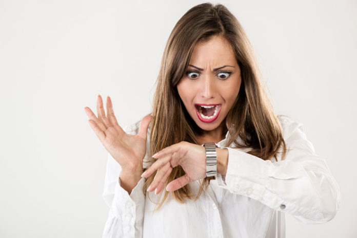 Woman looking at her watch and express a surprised emotion.